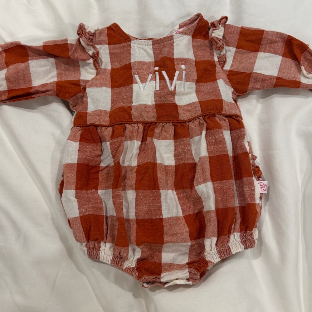 Ruffle Butts Burnt Orange and White Checkered Romper with “Vivi” embroidery.